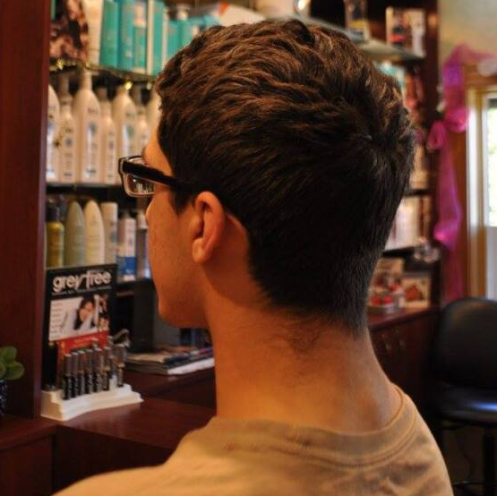 A man wearing glasses is sitting in front of a sign that says greyfree