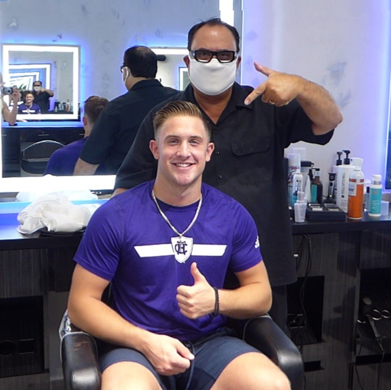 A man in a purple shirt is giving a thumbs up