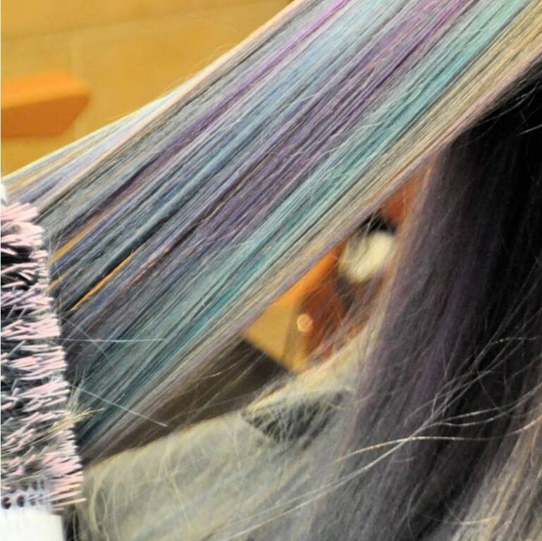 A close up of a woman 's hair with blue and purple highlights