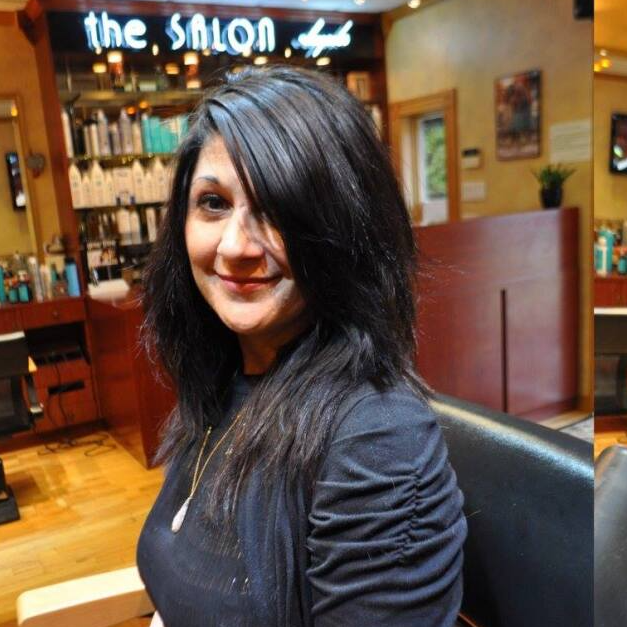 A woman sits in a chair in front of a sign that says the salon