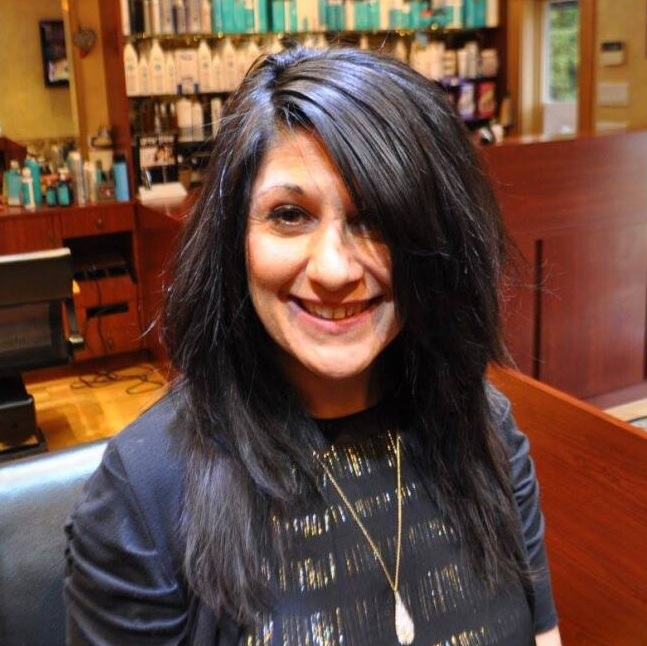 A woman with long dark hair is smiling for the camera