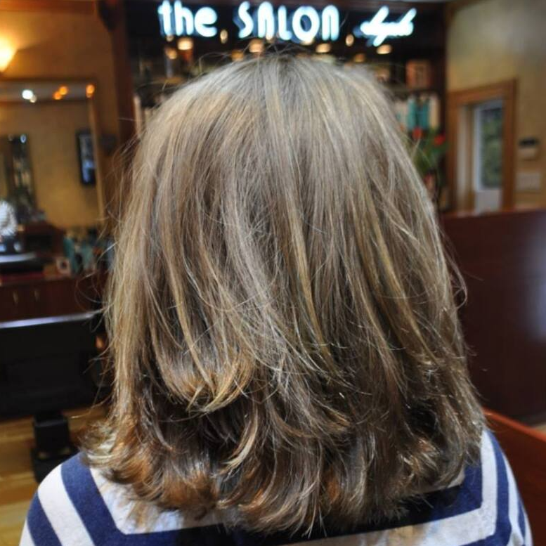 A woman 's hair is shown in front of a sign that says the salon