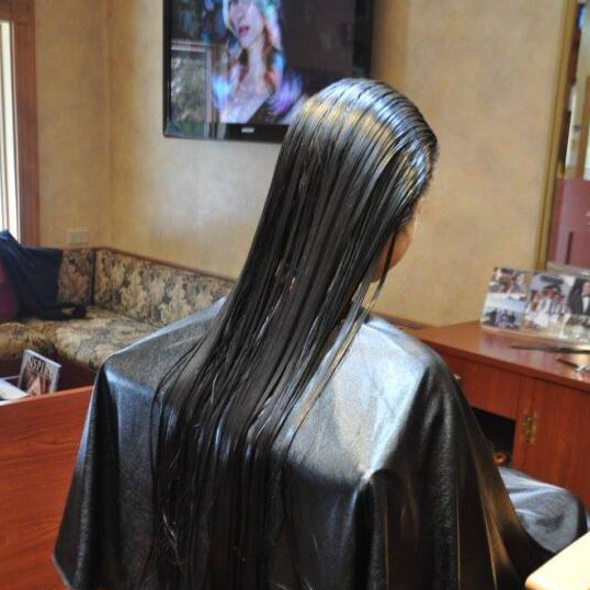 A woman in a black cape is getting her hair cut