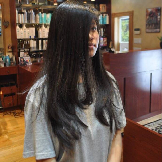 A woman with long black hair is standing in a salon