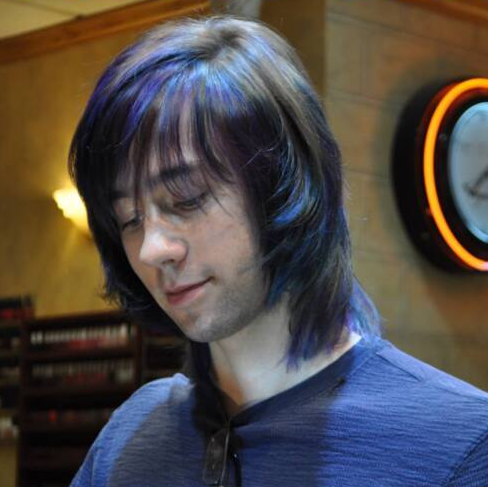 A man with purple hair is standing in front of a clock