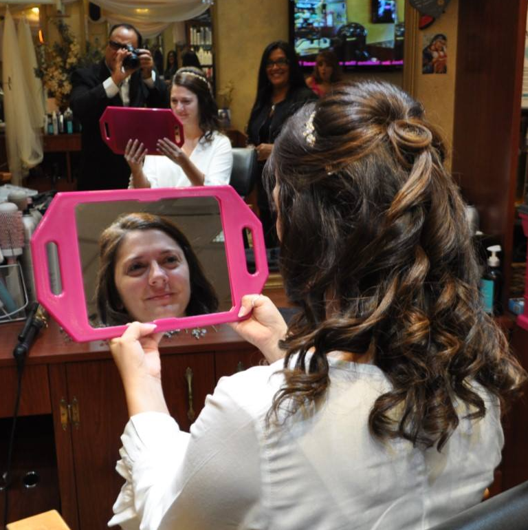 A woman is looking at her reflection in a pink mirror