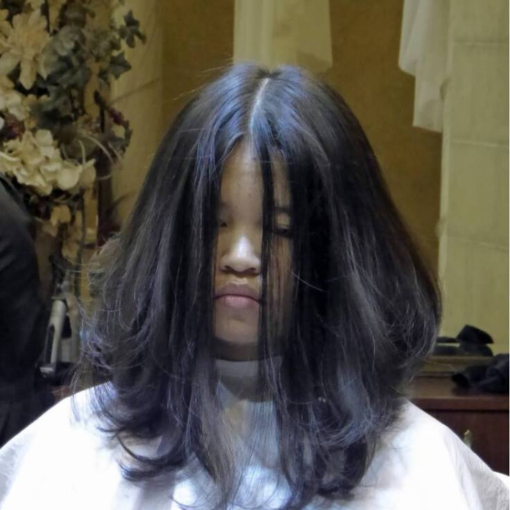 A woman with long black hair is wearing a white cape