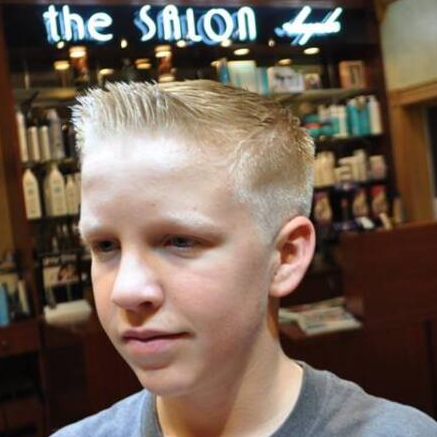 A young boy is standing in front of a sign that says the salon