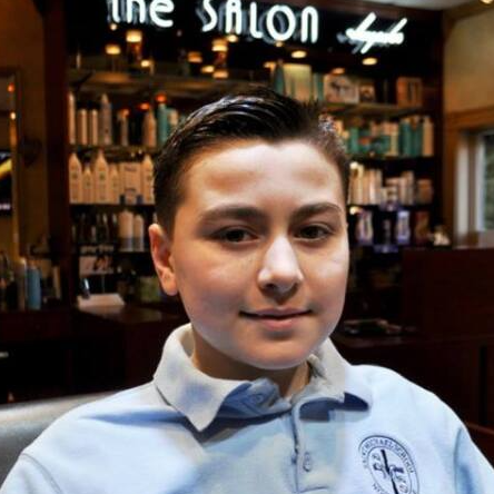 A young boy is standing in front of a sign that says the salon