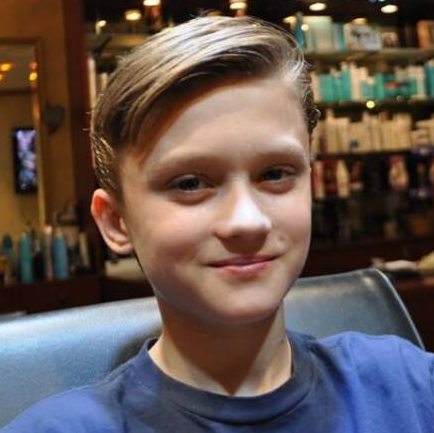 A young boy in a blue shirt is smiling for the camera