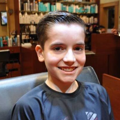 A young boy wearing an adidas shirt smiles for the camera