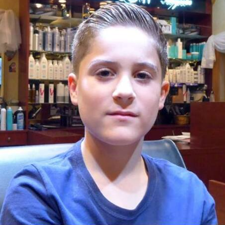 A young boy in a blue shirt is looking at the camera