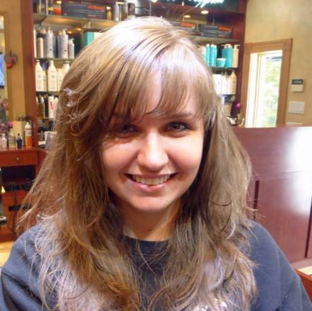 A woman with long hair is smiling in a salon