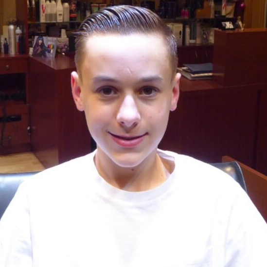 A young boy in a white shirt is smiling for the camera