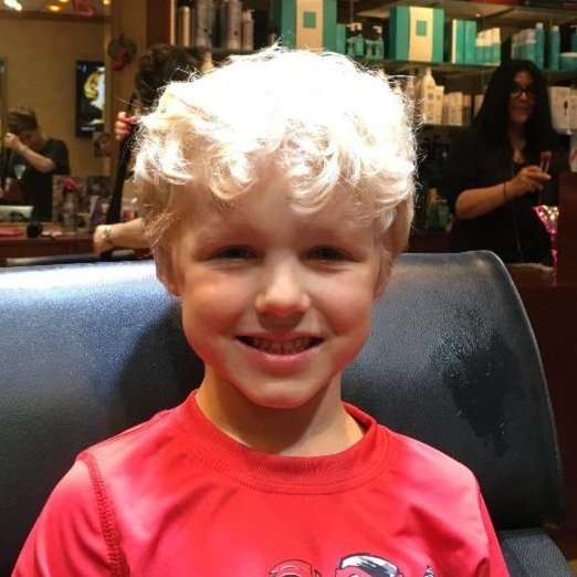 A young boy in a red shirt is smiling for the camera