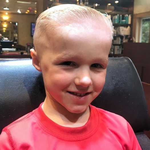 A young boy in a red shirt is smiling for the camera