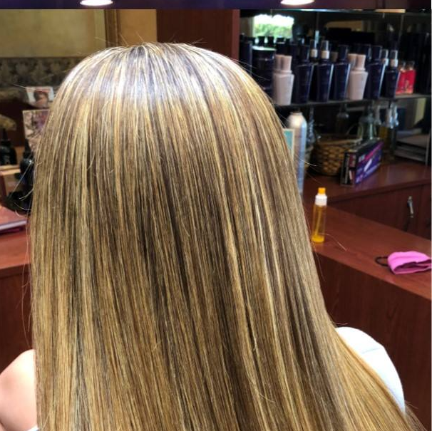 A woman with long blonde hair is sitting in front of a mirror