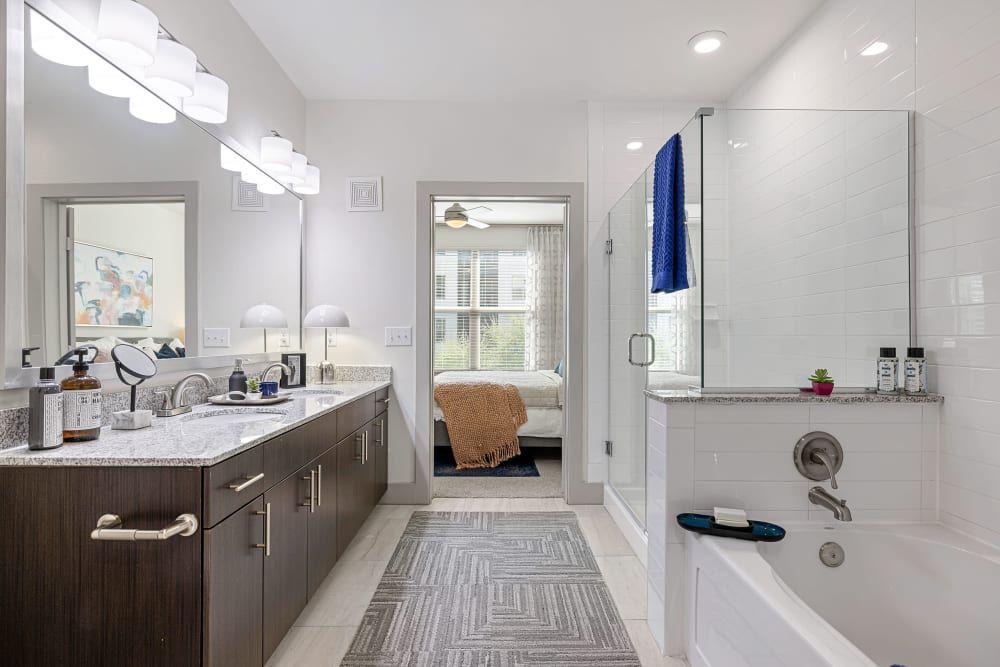 Master Bathroom with Double Sink Vanity, Bathtub, and Shower at The Nash Apartment Homes in Dallas, TX