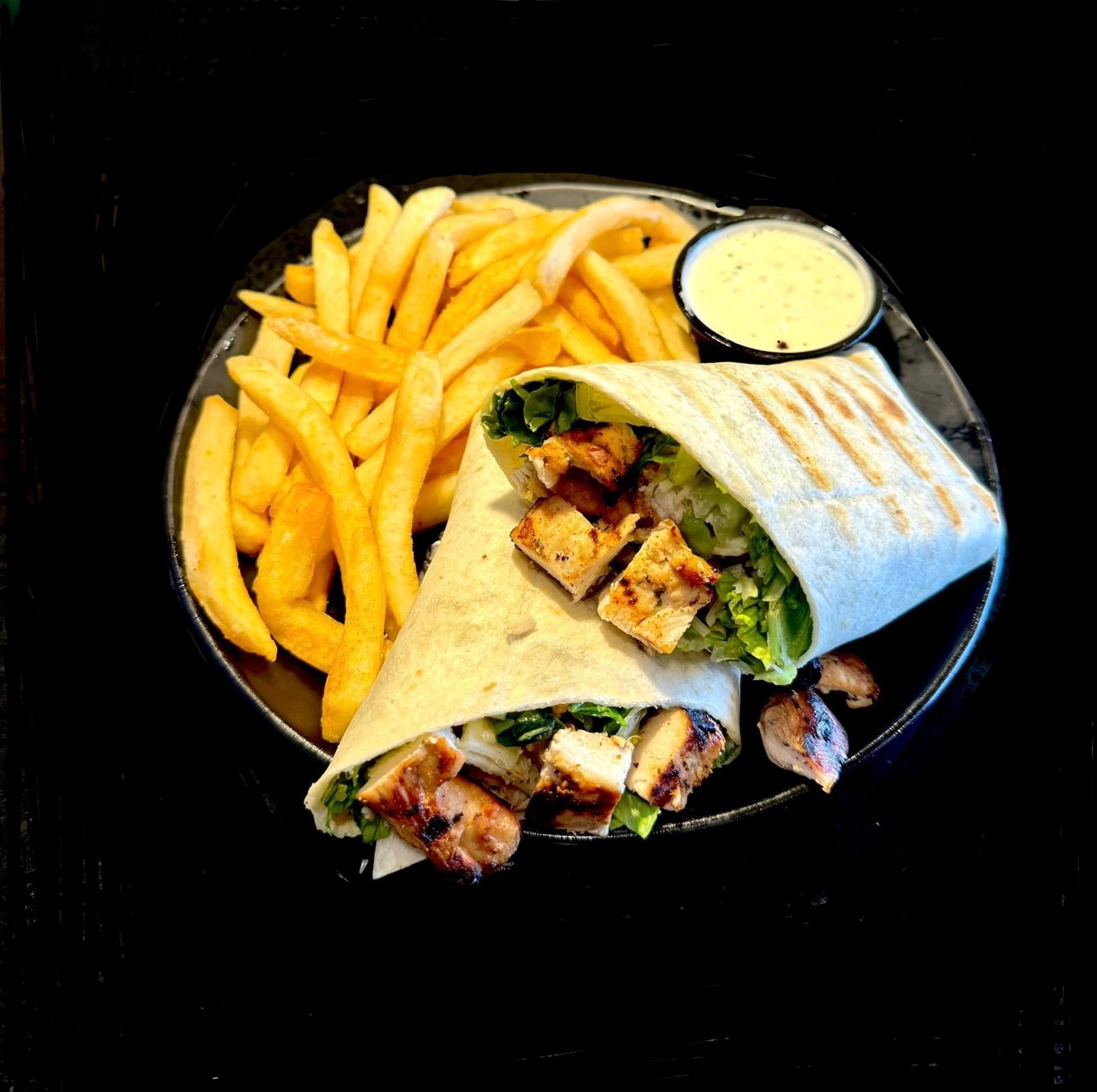 Chicken wrap with fries and dipping sauce on a black plate.