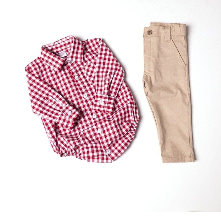Camisa a cuadros rojos y blancos y pantalones color canela colocados sobre una superficie blanca.