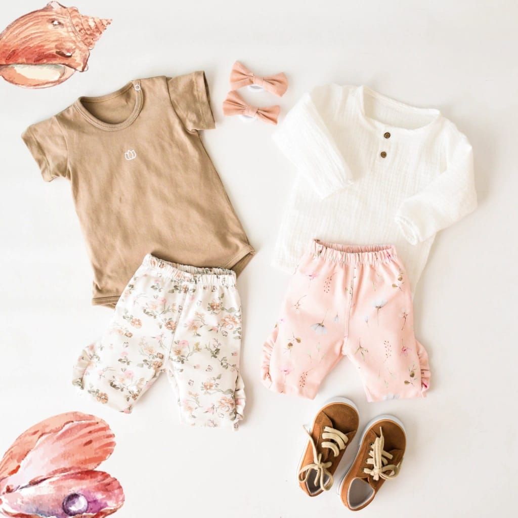 Ropa de bebé: mono marrón, pantalón floreado, top blanco, pantalón rosa, lazos y zapatos en color blanco.