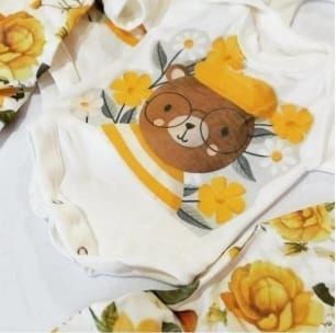 Body de bebé con osito con gafas y gorro, rodeado de flores.