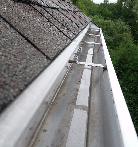 Clogged gutters causing water overflow and foundation damage on New Jersey home exterior