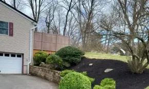 Landscaping installation with plants, mulch beds, and grading in residential yard