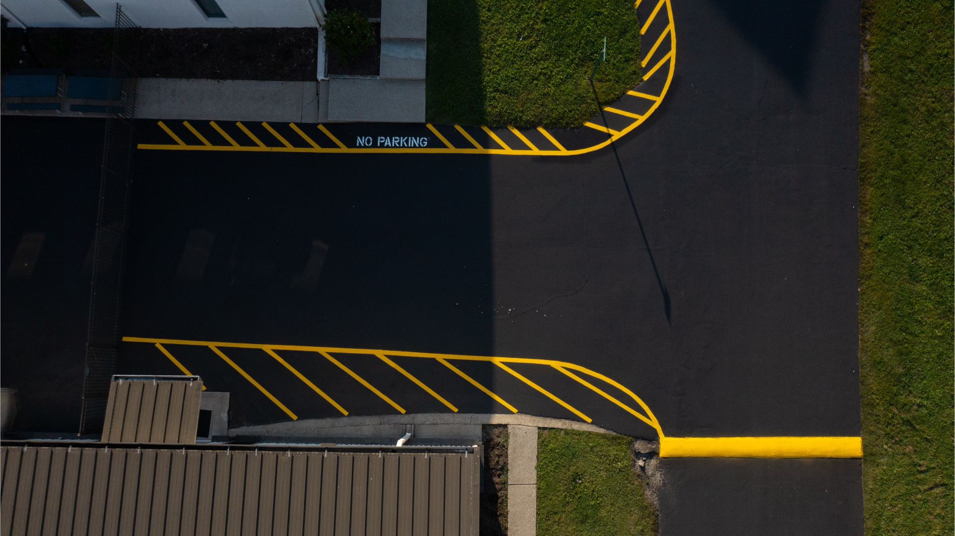 Freshly poured concrete sidewalk next to a building. Wooden straightedge lies at the bottom.