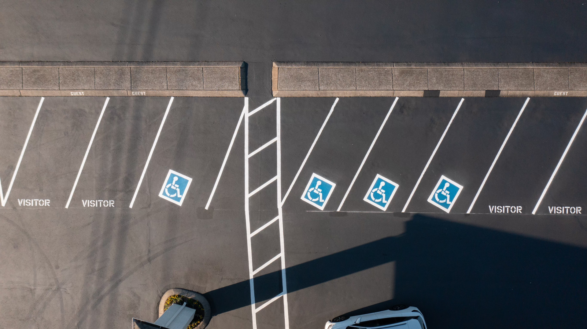 Asphalt patch being compacted by a small roller. Man in neon shirt watches. Outdoor setting.