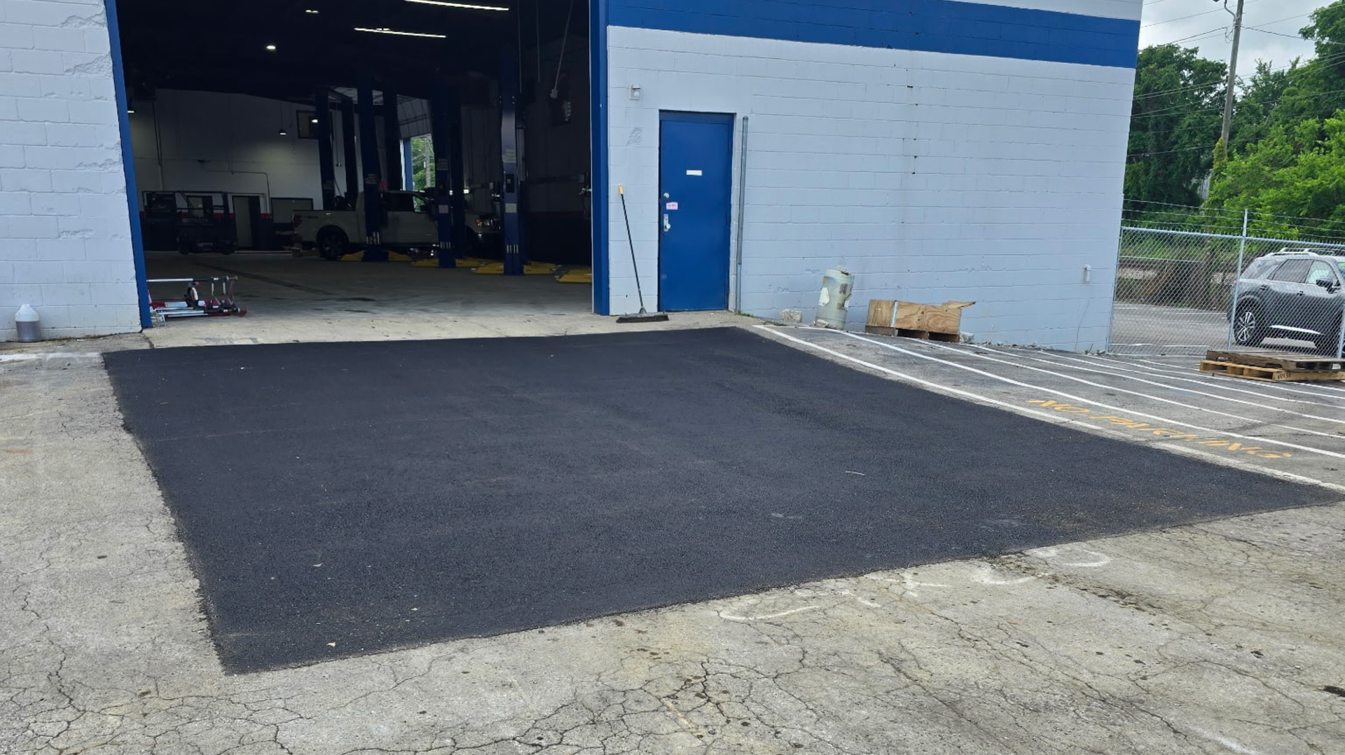 Aerial view of a church with a parking lot. White building with dark roof, surrounded by asphalt and green lawn.