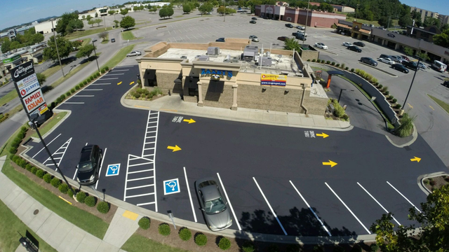 Aerial view of a restaurant with a freshly paved parking lot. Designated handicap parking spaces visible.