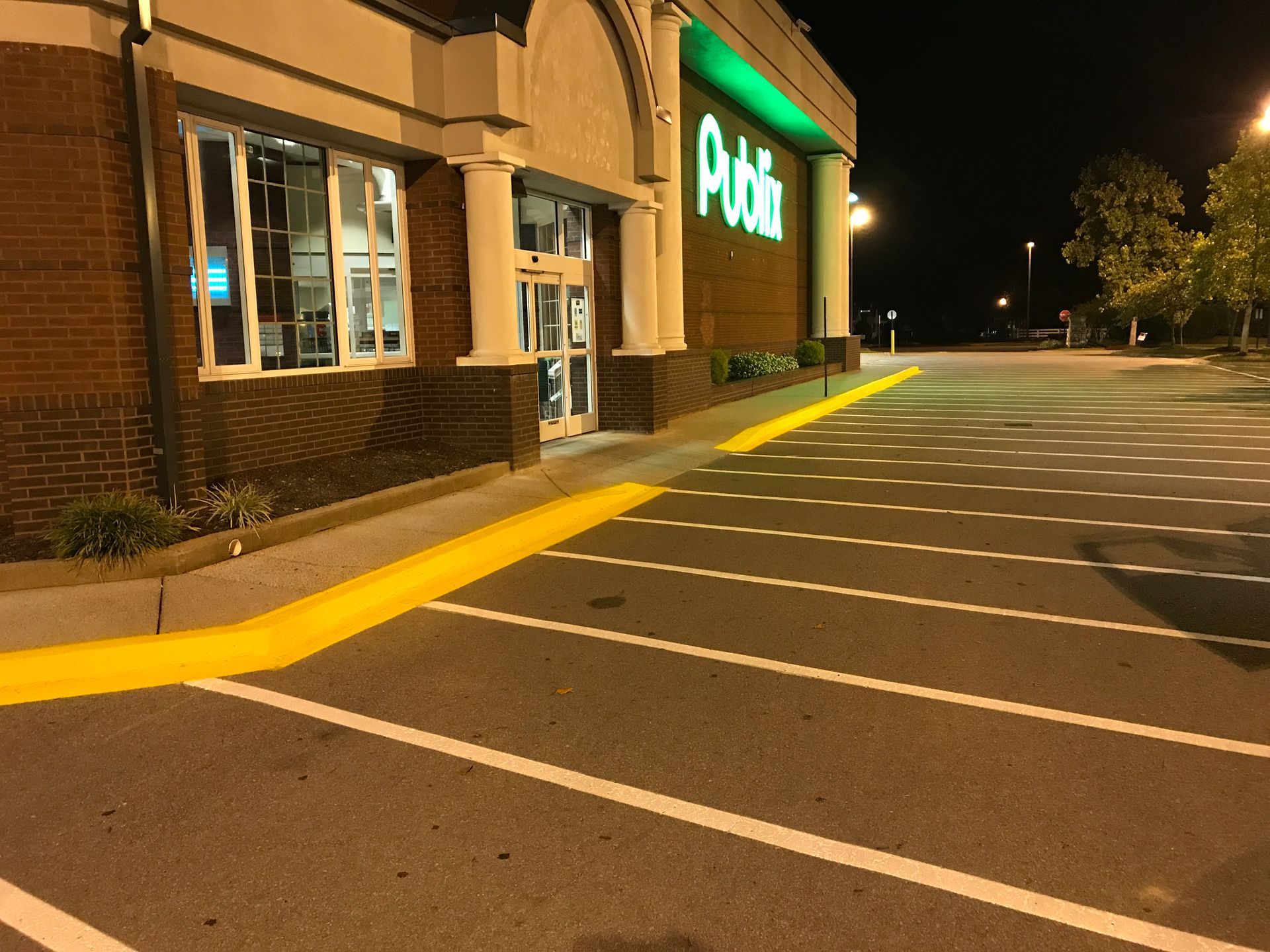 Asphalt patch being compacted by a small roller. Man in neon shirt watches. Outdoor setting.