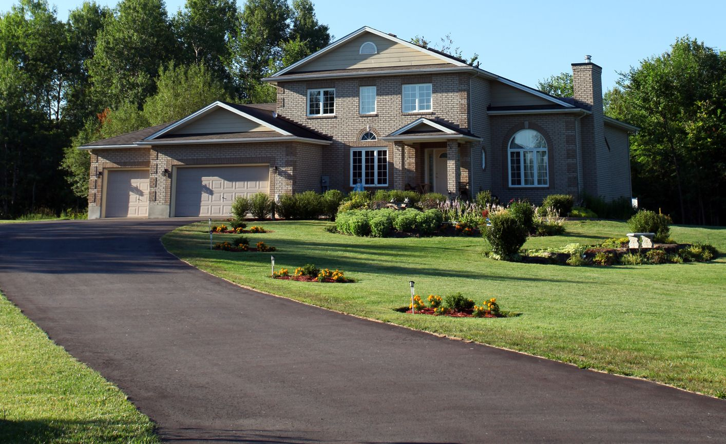 A two-story white house with a driveway and green lawn. A white mailbox is in front of the house.