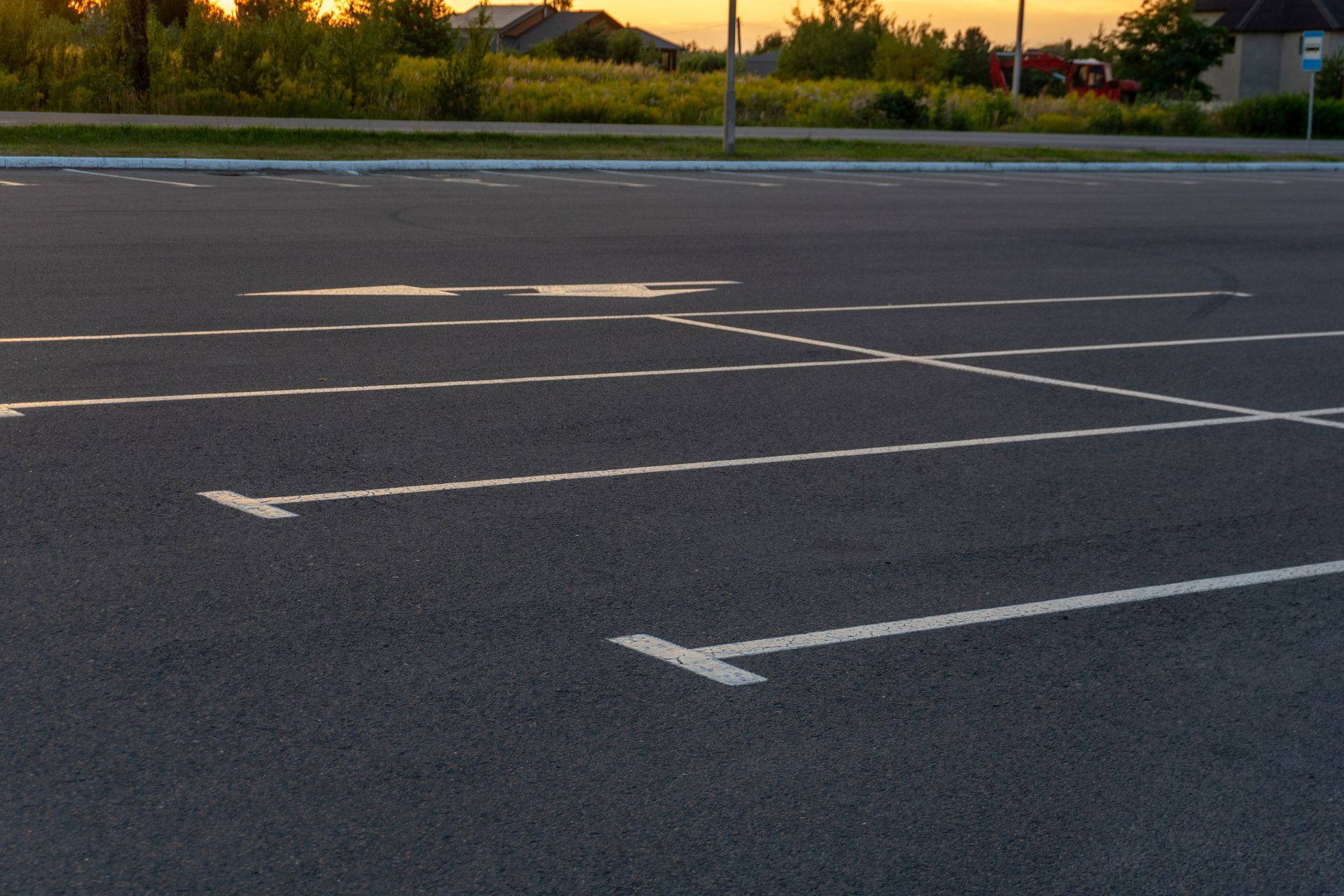 Asphalt patch being compacted by a small roller. Man in neon shirt watches. Outdoor setting.