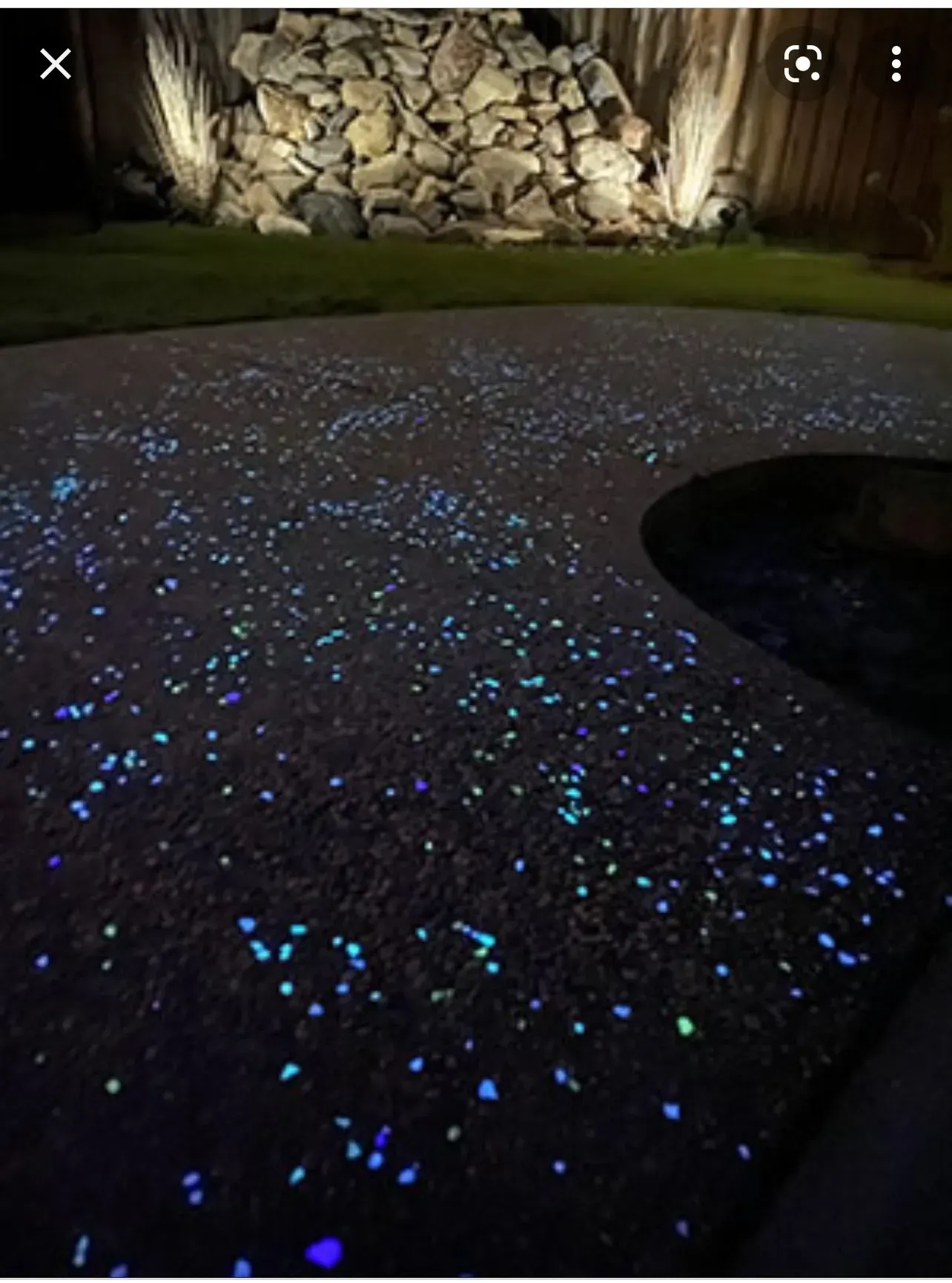 Glow-in-the-dark pebbles embedded in a patio. Blue, green, and purple pebbles illuminate the ground at night.
