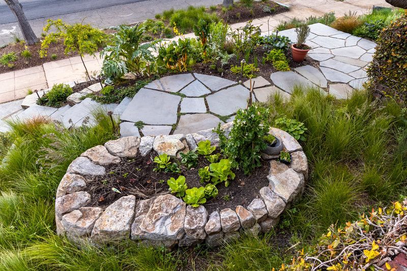 A garden with a circular stone planter filled with plants.
