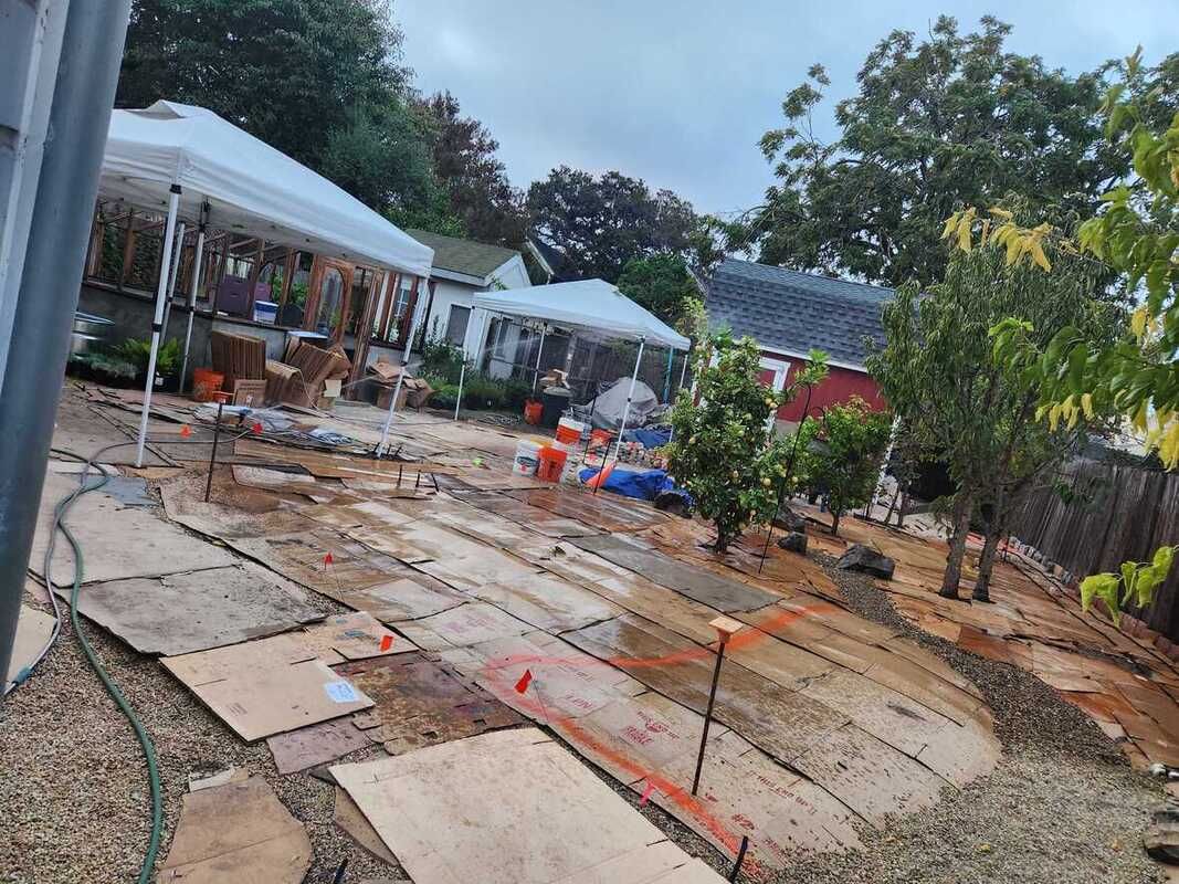 A backyard with a lot of wooden boards and a tent in the background.