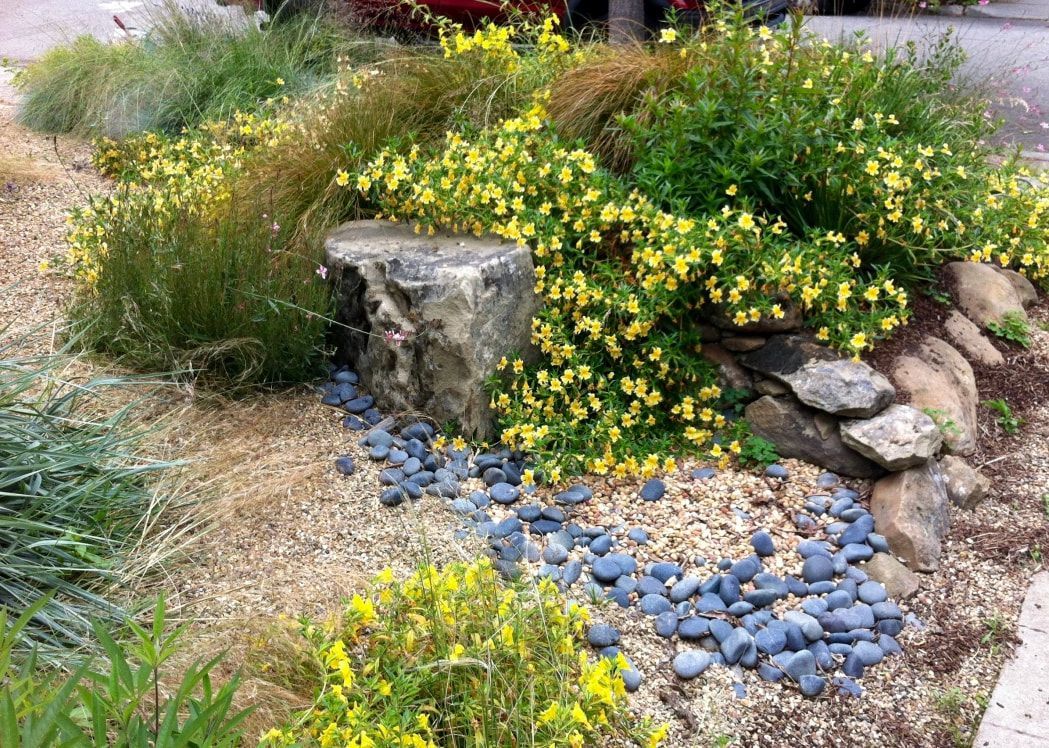 Three bowls filled with rocks and flowers are sitting on the ground.