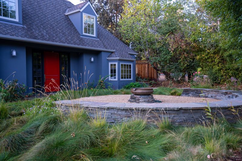 A blue house with a red door and a fire pit in front of it.