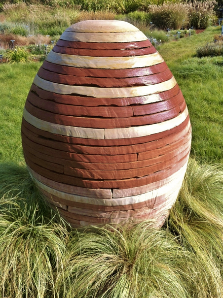 A large brown and white sculpture is sitting in the grass.