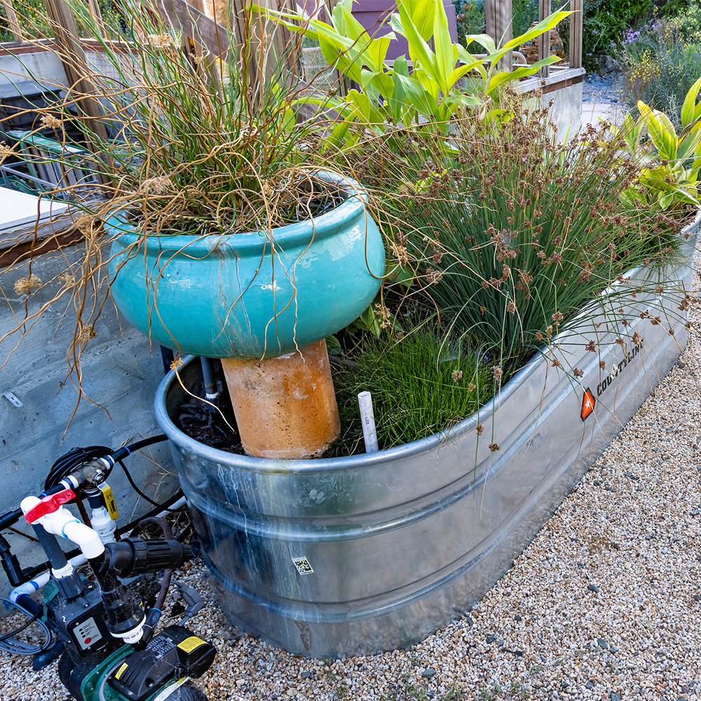 A metal tub filled with potted plants and flowers.