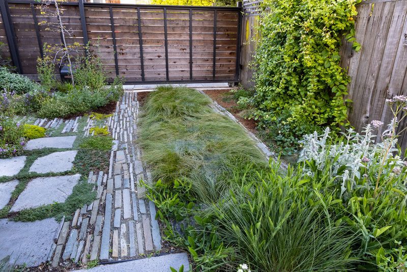 A garden with a stone walkway and a wooden gate.