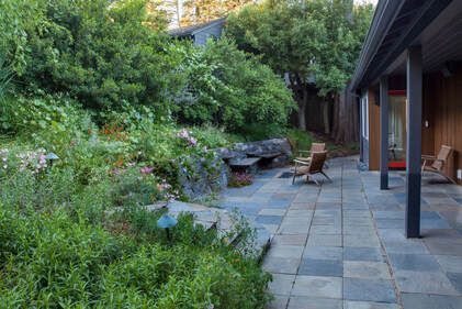 A patio with chairs and a fire pit in the backyard of a house.