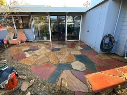 A stone patio is being built in front of a house.