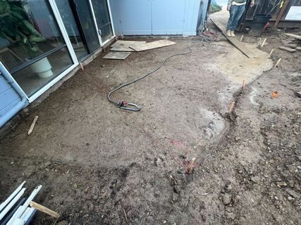 A person is digging in the dirt in front of a house.