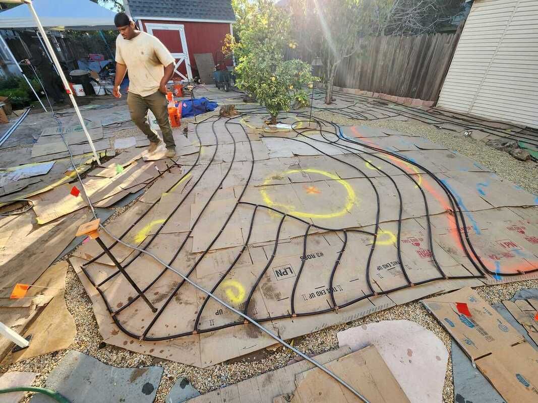 A man is standing in front of a cardboard maze in a backyard.