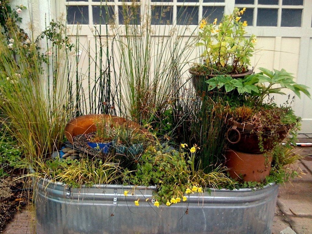 A metal tub filled with potted plants and flowers