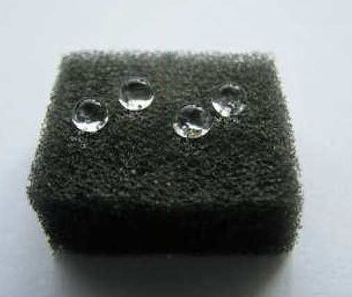 Three water drops are sitting on top of a black sponge.