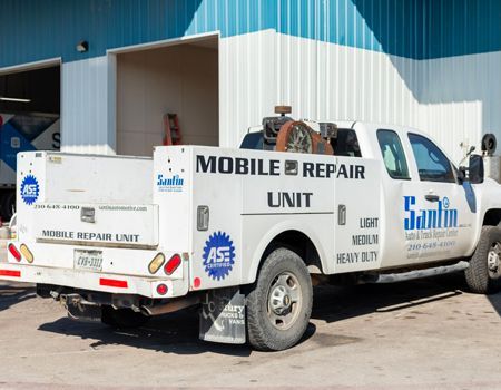 White mobile repair truck parked outside a building, with